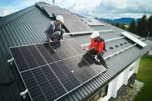 Men workers installing solar panels on roof of house.