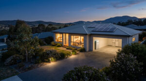 A brightly lit Tasmanian home during a nighttime power outage, powered by rooftop solar panels and a home battery system in the garage, designed by Expert Energy Tasmania to keep families blackout ready
